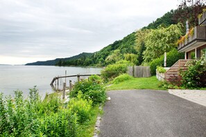 Una propiedad junto al lago con un sendero pavimentado, muelle de madera y abundante vegetación.