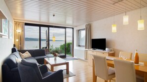 A modern living room with a sofa, coffee table, and dining area. - Apartment '1, 70sqm' with Large Terrace Right on the Lake (Bodman-Ludwigshafen)
