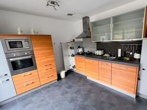 Une cuisine moderne dotée d’appareils électroménagers intégrés, d’armoires en bois et d’un sol carrelé.