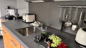Cocina moderna con un lavamanos doble, un tostador y un bloque de cuchillos con un cuchillo sobre una tabla de cortar.
