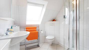 Une salle de bain moderne avec un lavabo blanc, une douche en verre et des toilettes.