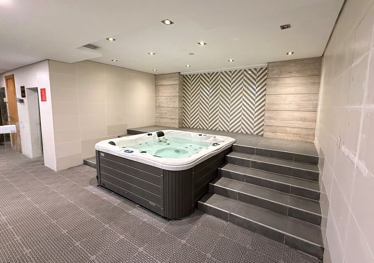 Un baño moderno con una bañera independiente grande y una escalera que conduce a un nivel superior, además de un revestimiento de pared con diseño.