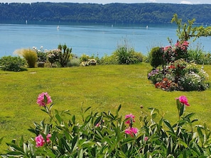 A grassy area with flowers and a lake with boats.