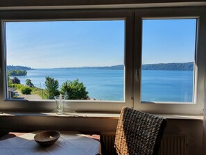 Una habitación con una mesa, una silla y vista a un lago a través de una ventana.