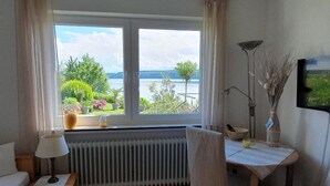 A room with a view of a lake, a radiator, a desk with a lamp, and a chair. - Apartment 'Panorama-seetraum' with Lake View, Private Terrace and Wi-Fi (Sipplingen)