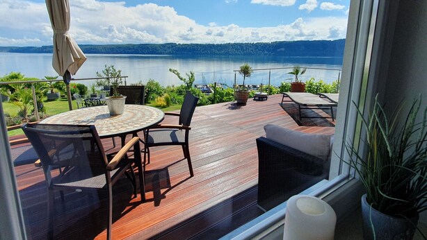 A deck with a table and chairs, overlooking a lake and distant mountains. - Apartment 'Panorama-seetraum' with Lake View, Private Terrace and Wi-Fi (Sipplingen)