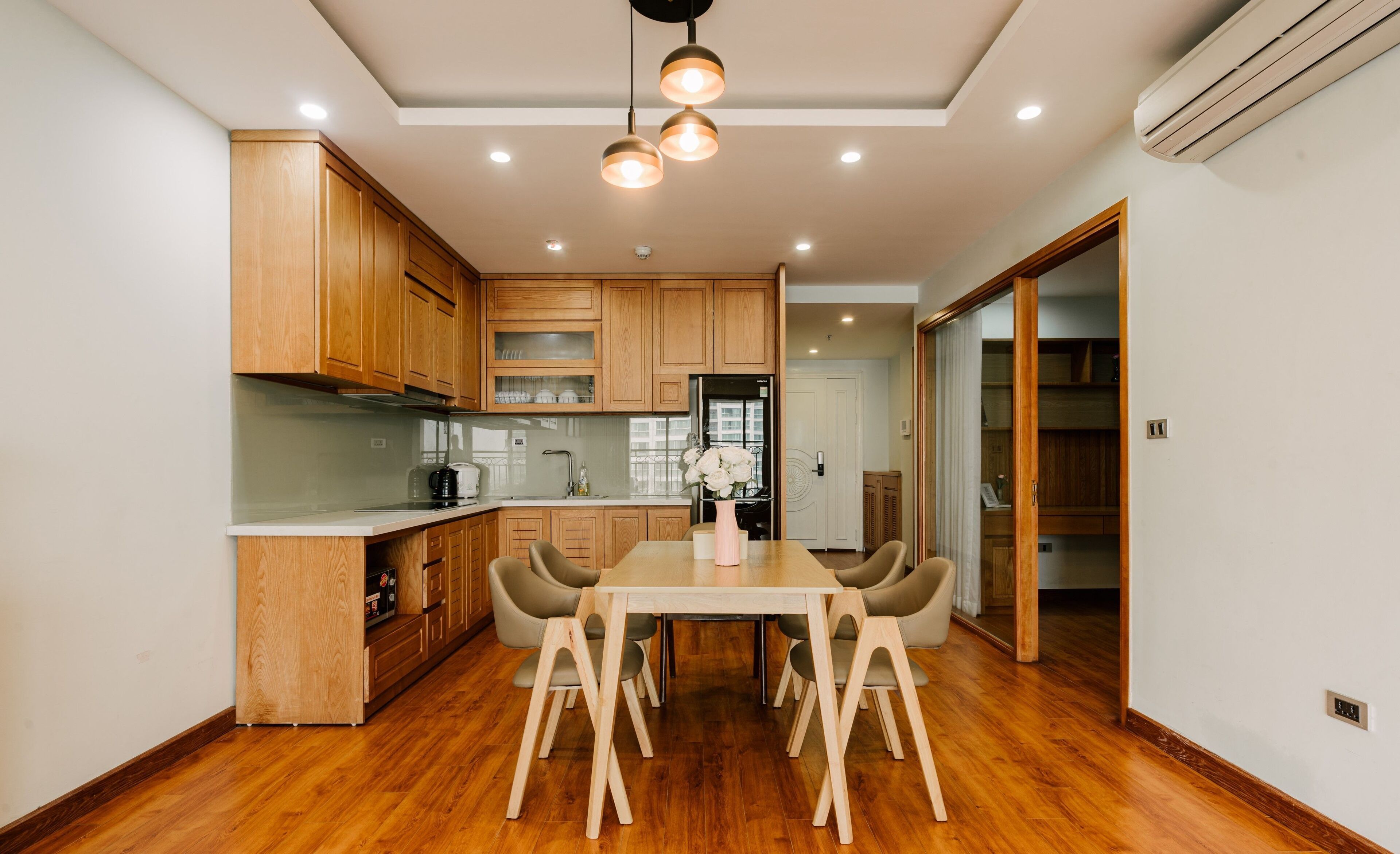 Una cocina moderna con armarios de madera, una mesa de comedor con sillas y un refrigerador.