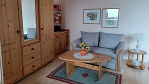 A cozy living room with a wooden wardrobe, a grey sofa, a wooden coffee table, and a small side table with a lamp. - Apartment 'Koberstaedt' Panoramic Lake View, Balcony and Wi-Fi (Meersburg)