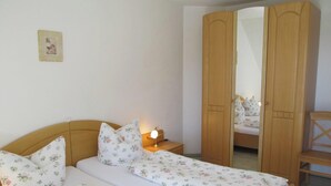 Un dormitorio con cama, mesita de noche, espejo y armario.
