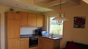 Una cocina con armarios de madera, estufa, lavabo y ventana con vista a zonas verdes.