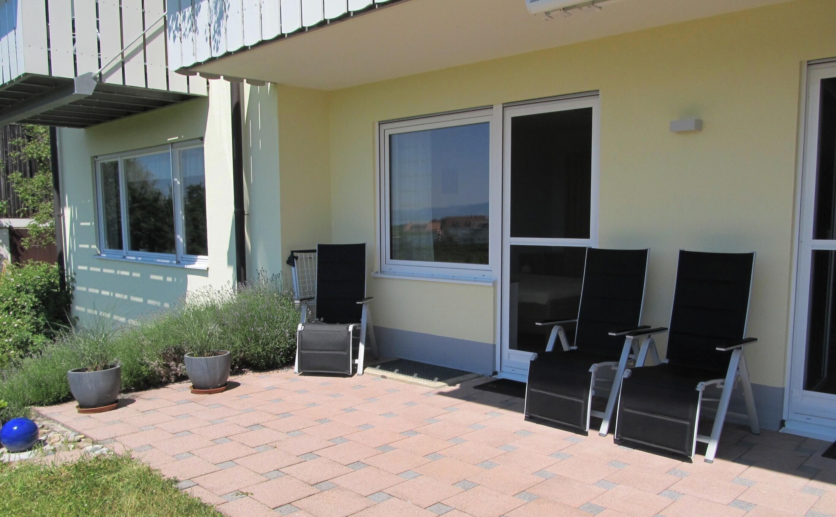 Un patio con mobiliario exterior, una ventana y una puerta.