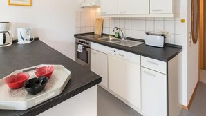 Een compacte keuken met witte kasten, een zwart aanrecht, een fornuis, een spoelbak en een broodrooster.