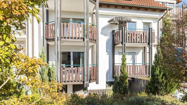 Un immeuble à plusieurs étages doté de balcons, d’une clôture en bois et surplombant un ciel dégagé.