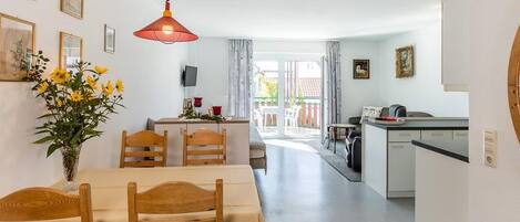Ein Essbereich mit Tisch und Stühlen, einer Blumenvase und einer Küche im Hintergrund.
