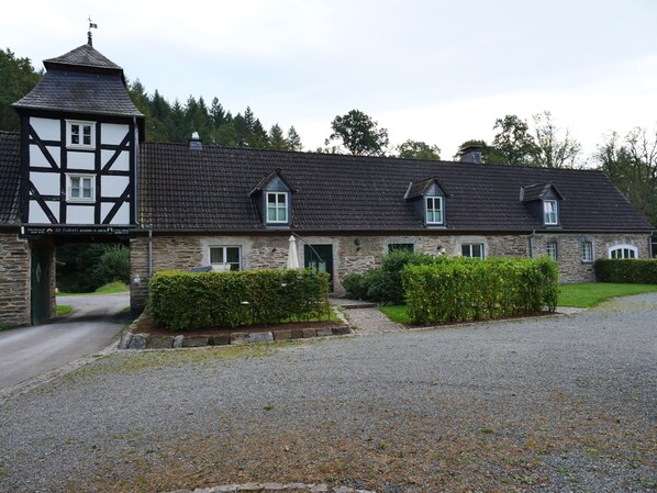Un bâtiment en pierre avec une façade noire et blanche, de nombreuses fenêtres et une allée gravillonnée.