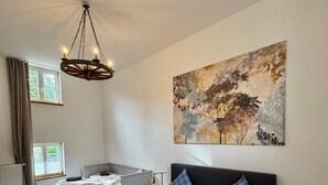 Un dormitorio con cama, mesita de noche, cortinas en la ventana, un radiador y un cuadro en la pared.