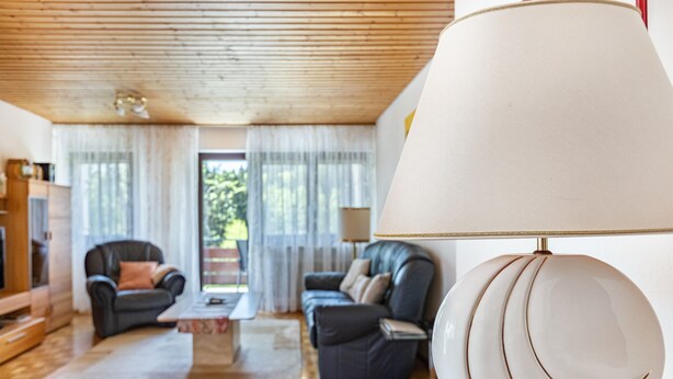 Un salon moderne avec un plafond en bois, deux canapés en cuir, une table basse et un grand lampadaire.