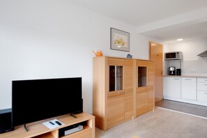 A modern kitchen with white cabinets, a microwave, and a coffee maker.