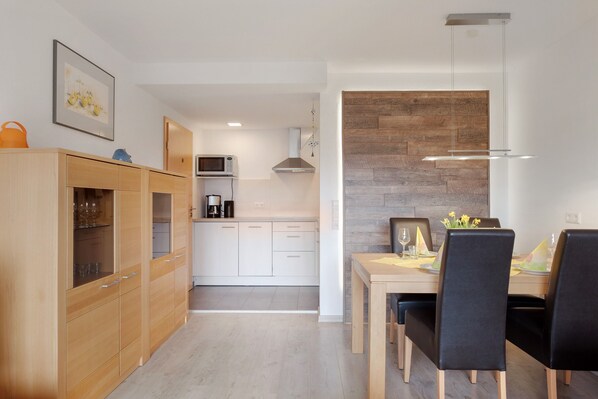 A modern kitchen with white cabinets, a microwave, and a hanging light fixture.