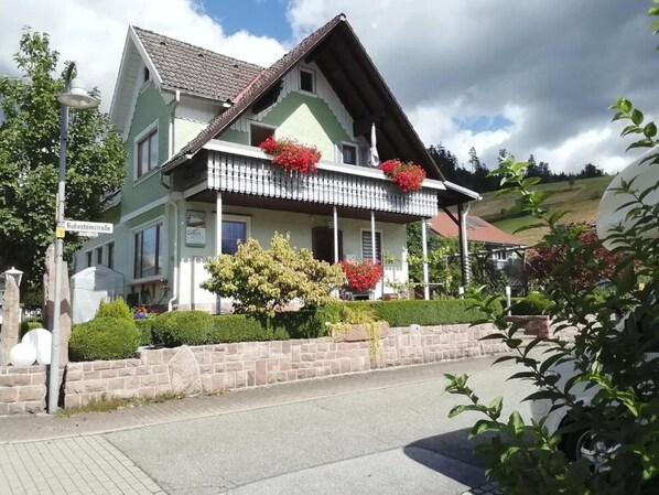 A traditional house with a balcony, a stone wall, and a street lamp.