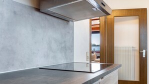 Une cuisine moderne dotée d’un plan de travail élégant, d’une cuisinière intégrée et d’une porte en bois.