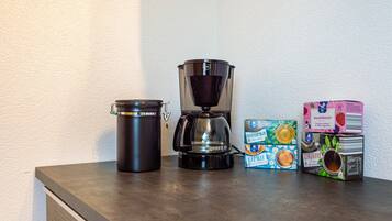 A coffee maker, a thermos, and boxes of coffee on a countertop.