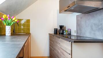 A modern kitchen with a built-in stove, a coffee maker, and a vase with tulips on the counter.