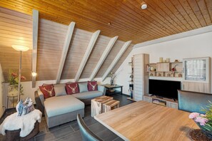 Une chambre moderne de style loft, avec un plafond en bois, un canapé, une table à manger et un téléviseur.