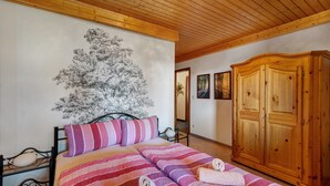 A bedroom with a bed, wooden wardrobe, and a wall with a tree mural. - Apartment 'Karin' with Lake View and Balcony (Schonach)