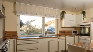 Una cocina moderna con un amplio ventanal, electrodomésticos integrados y un comedor.