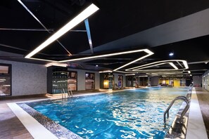 An indoor swimming pool with modern lighting fixtures, a clear pool area, and a lounge area with seating and a bar. - D El Dorado Westlake Luxury Apartments (Hanoi)