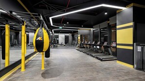 Una palestra con attrezzature per esercizi, un sacco da boxe e uno specchio a parete.