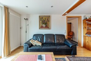 Un salon avec un canapé en cuir noir, une table basse en bois, un lampadaire et un tableau accroché au mur.