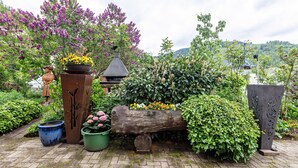 Een tuin met een houten bank, potplanten en een standbeeld.