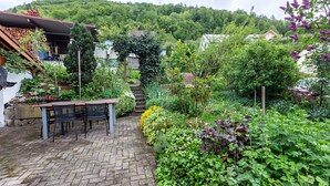 Een tuin met een terras van baksteen, een tafel en stoelen.
