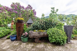 A garden with a wooden log bench, potted plants, and a statue.