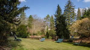 Ein Park mit grünem Gras, Bäumen und Bänken.
