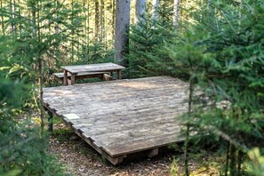 A wooden deck with a picnic table in a forested area. - Trekking Camp on the Renchtalsteig – Campsite (Oppenau)