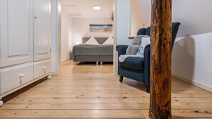 Ein Zimmer mit Bett, Stuhl, Kleiderschrank und einem Holzbalken.