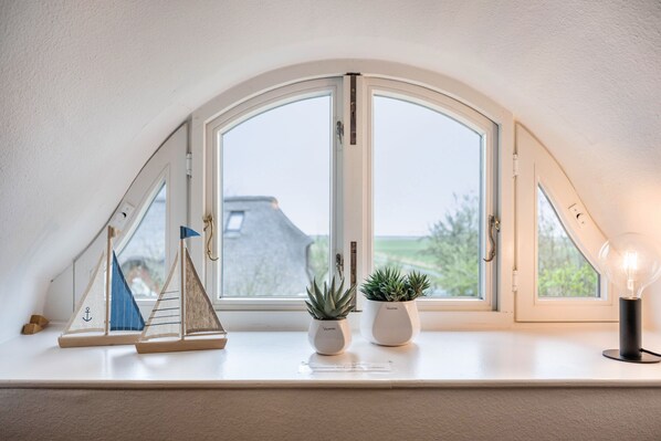 A skylight window with two potted plants and a light bulb on a white ledge.