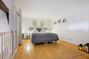 Une chambre à coucher avec un lit, un plancher en bois, une table de chevet et des lampes fixées au mur.