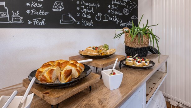 A breakfast buffet with bread, pastries, and a chalkboard menu. - Knutzenswarft - Holiday Apartment "Möwe" (Westerhever)