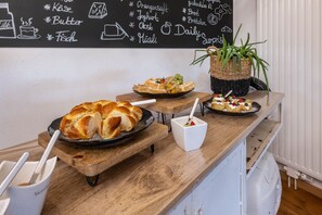Buffet de l'esmorzar amb pa, pastissos i un menú escrit en pissarra.
