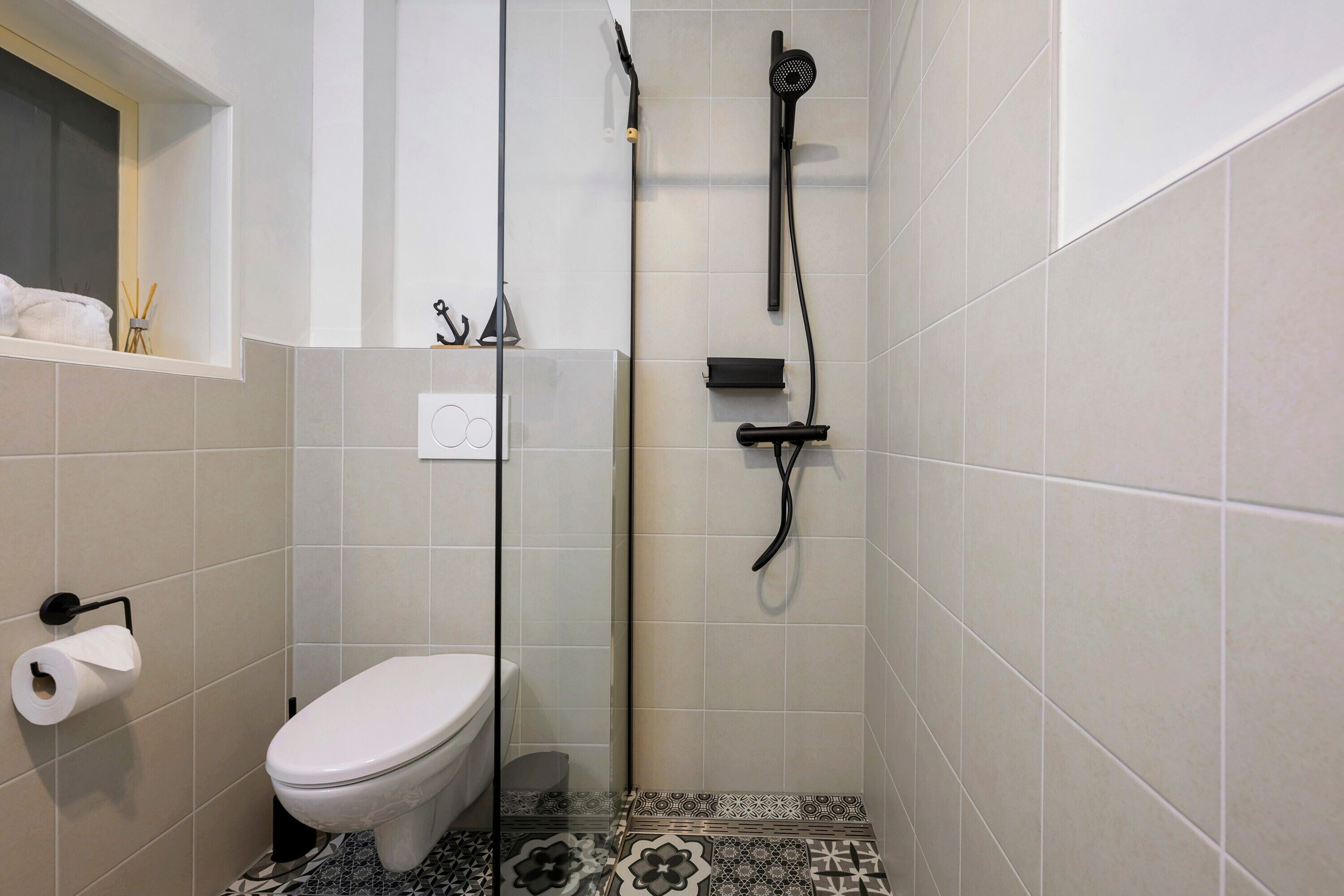 A bathroom with a toilet, a shower with a handheld showerhead, and a towel rack.