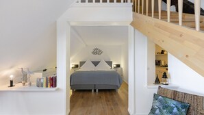 Um quarto com uma cama, mesa de cabeceira, abajur e estante de livros.