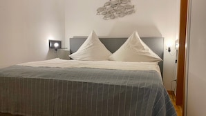 Un lit bien fait, avec une couvre-lit à rayures, une tête de lit et un luminaire fixé au mur.