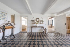 Een kamer met een geruit vloertje, een houten tafel met hangplanten en een vintage naaimachine.