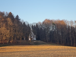 Un paisaje rural con un campo, árboles y un edificio a lo lejos.