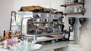 Una cafetera con molinillo, espumador de leche y vaporera.