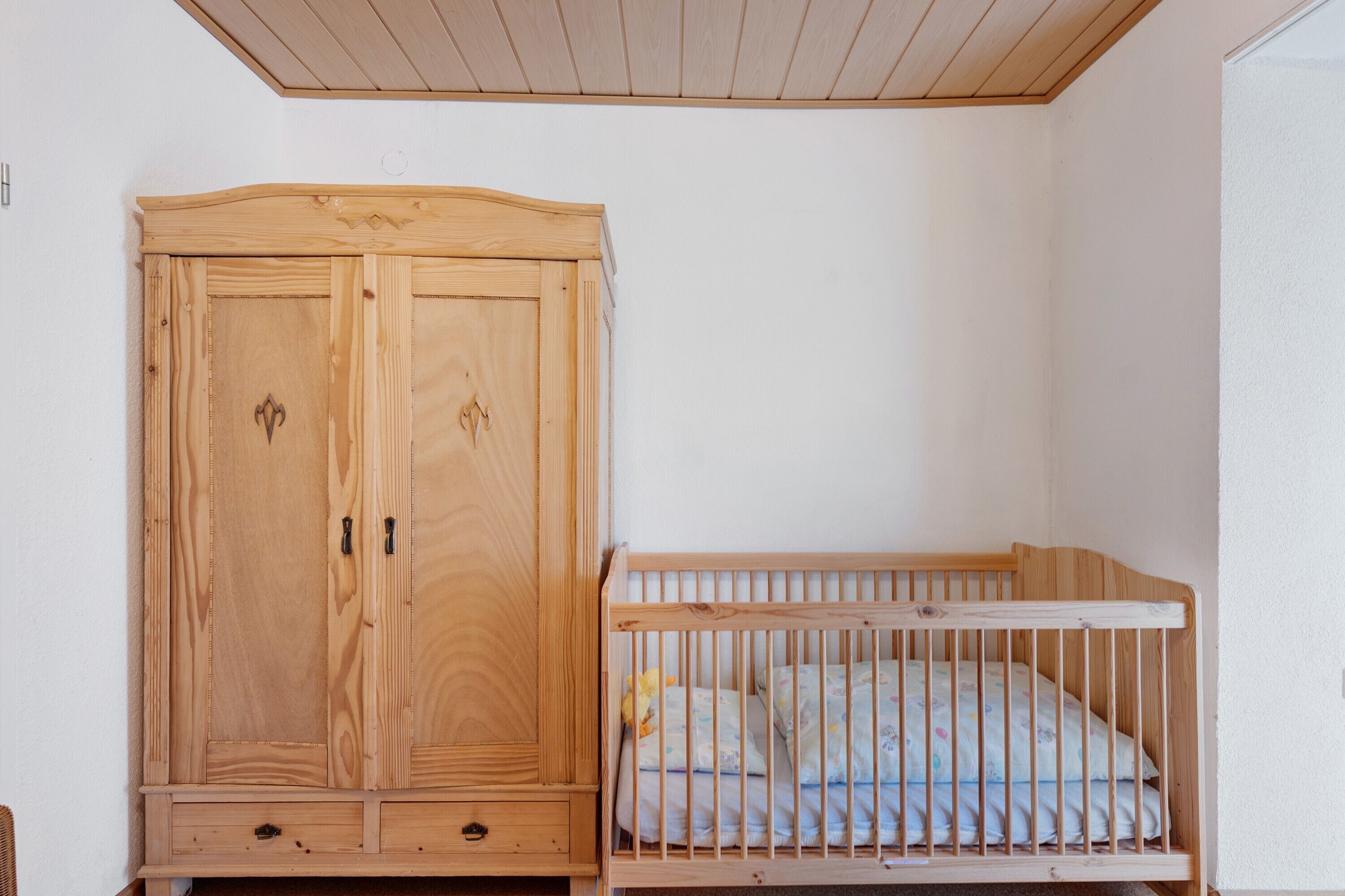 Ein Holzschrank mit zwei Türen und ein Gitterbett mit Holzrahmen und Matratze.